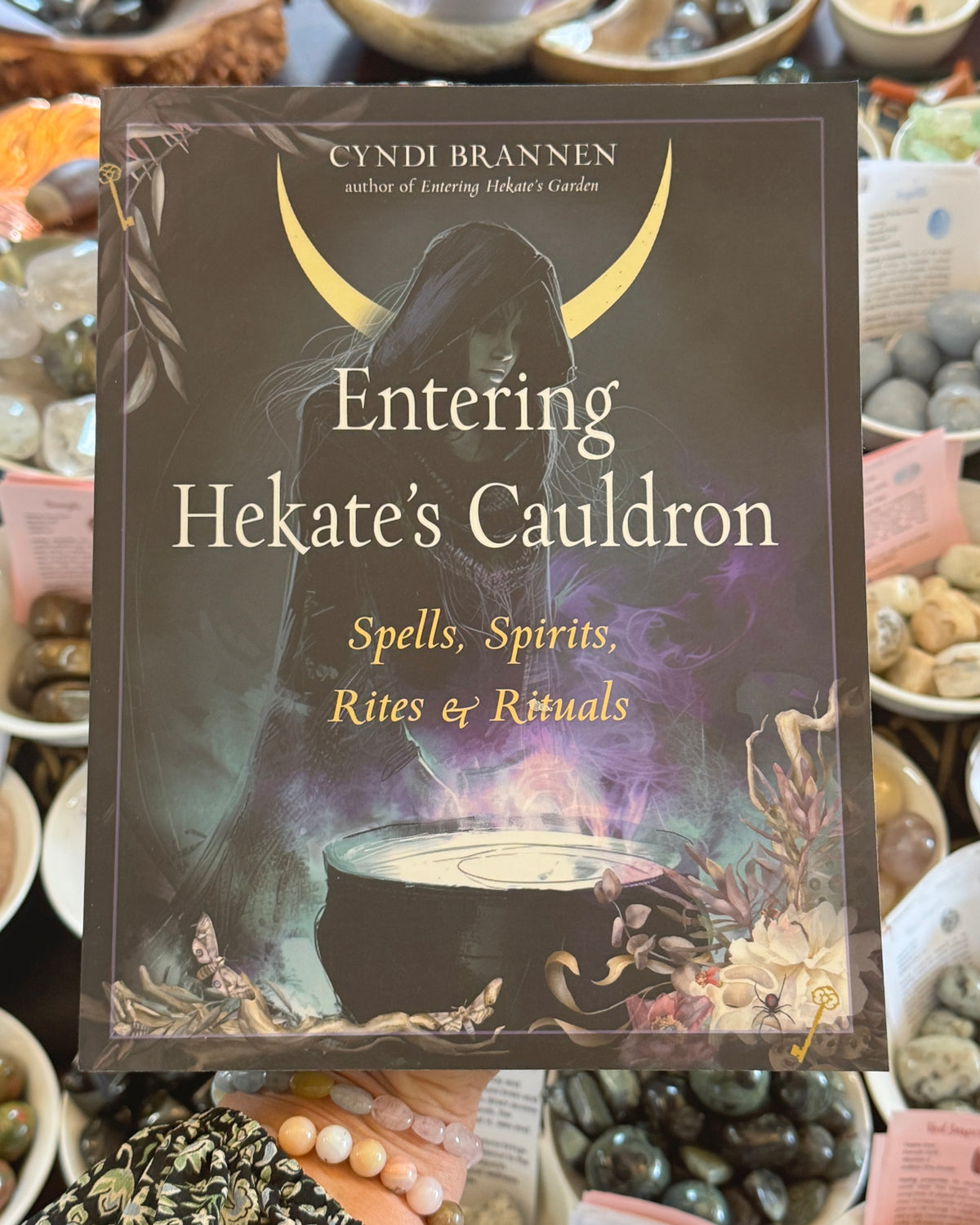 Entering Hekate’s Cauldron by Cyndi Brannen, witchcraft book featuring Goddess Hekate, a magical cauldron, crescent moon, sacred herbs and mystical purple flames, spells, spirits, rites and rituals.