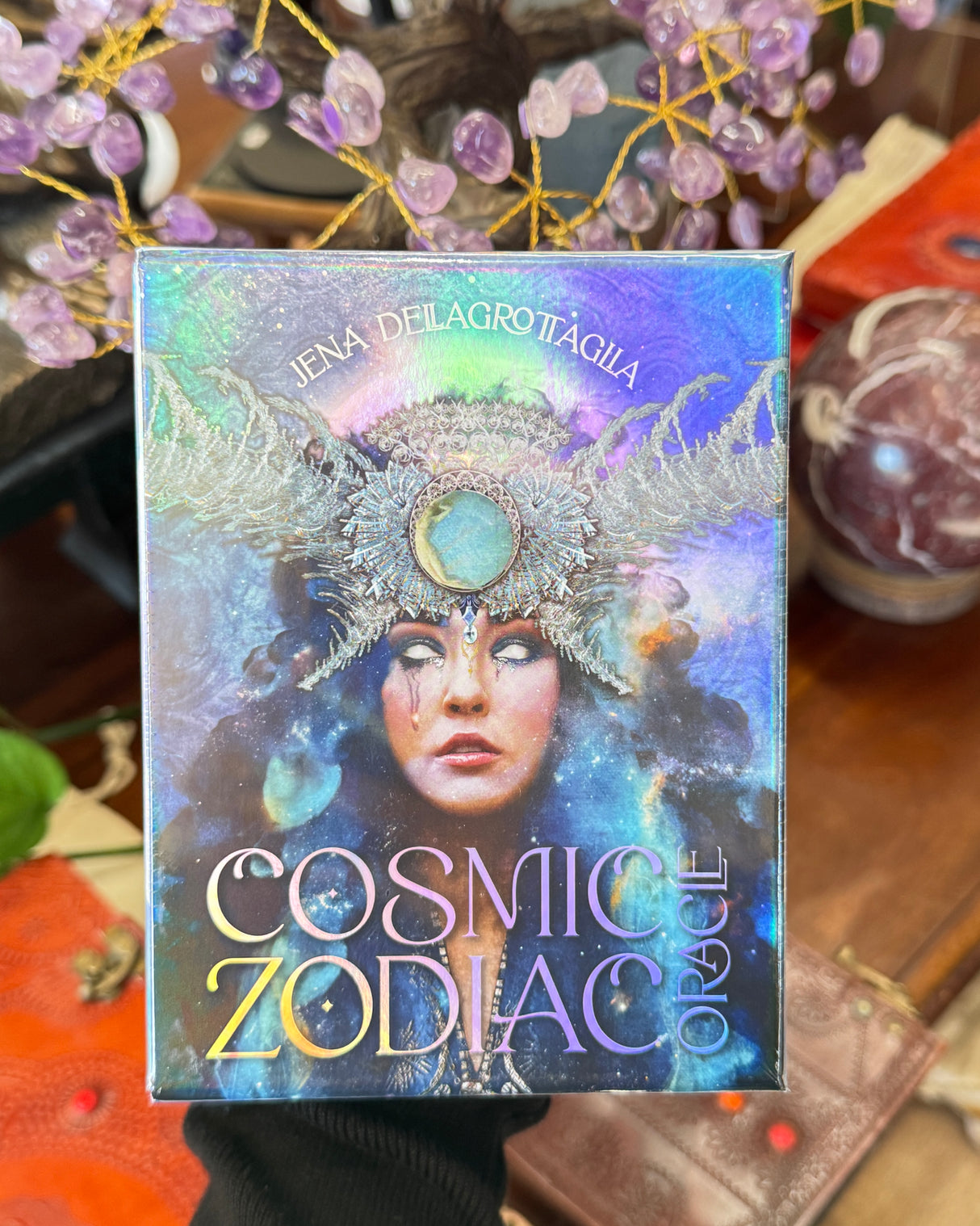 Cosmic Zodiac Oracle card deck by Jena Dellagrottaglia with holographic celestial artwork and mystical zodiac-themed design.