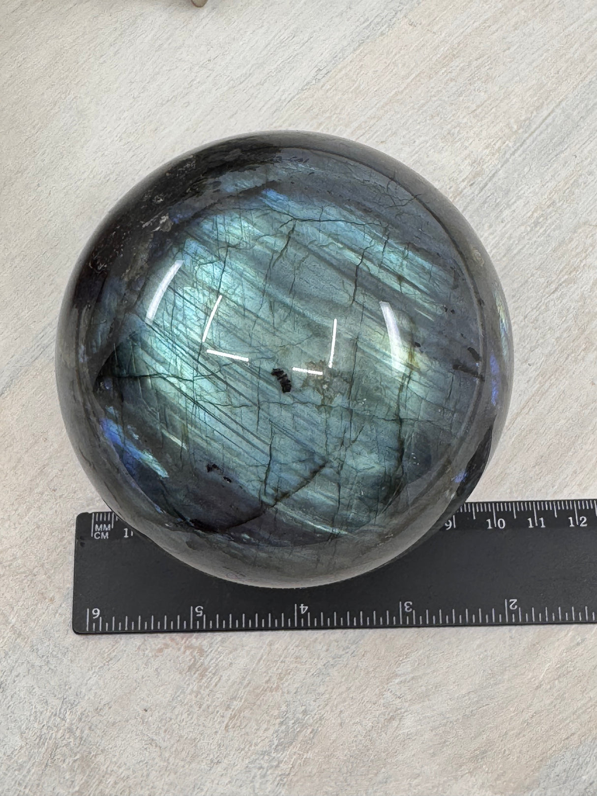 Labradorite sphere 1.288kg – blue and gold flashes crystal ball next to a ruler measuring 10cm