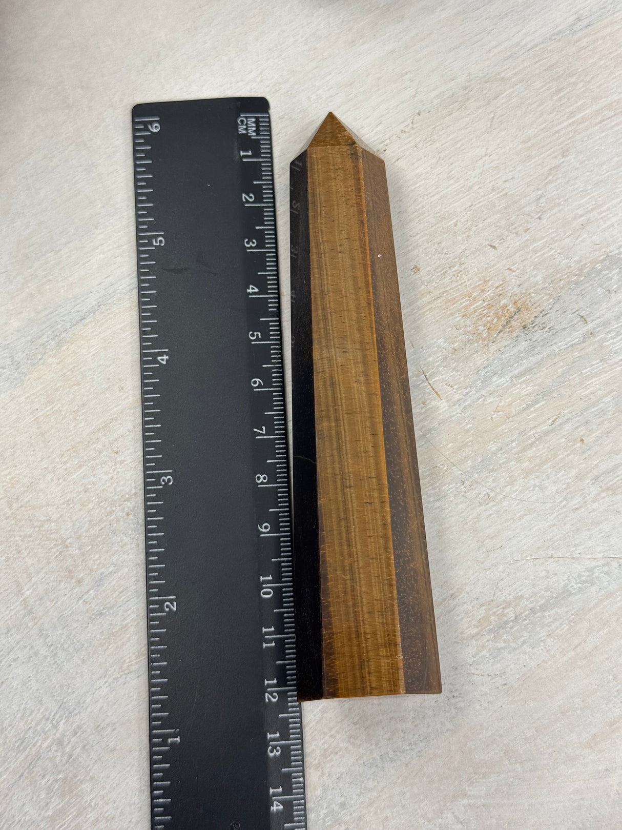 6-Sided Tiger Eye Point 12 cm × 3 cm – golden-brown crystal point symbolising courage, grounding and strength, Inspired By 3 Australia. showing measurement with ruler
