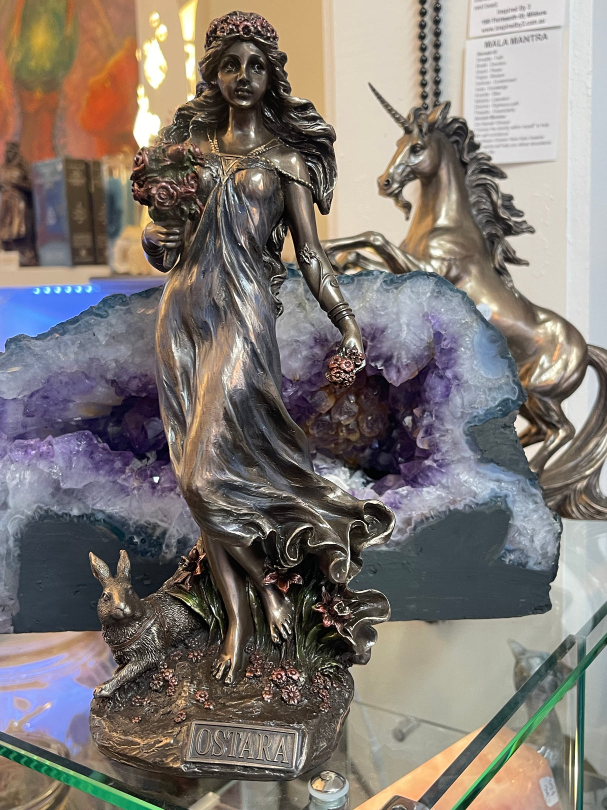 "Ostara bronze statue surrounded by flowers, hares and eggs – Goddess of Spring and renewal, symbol of fertility and new beginnings"