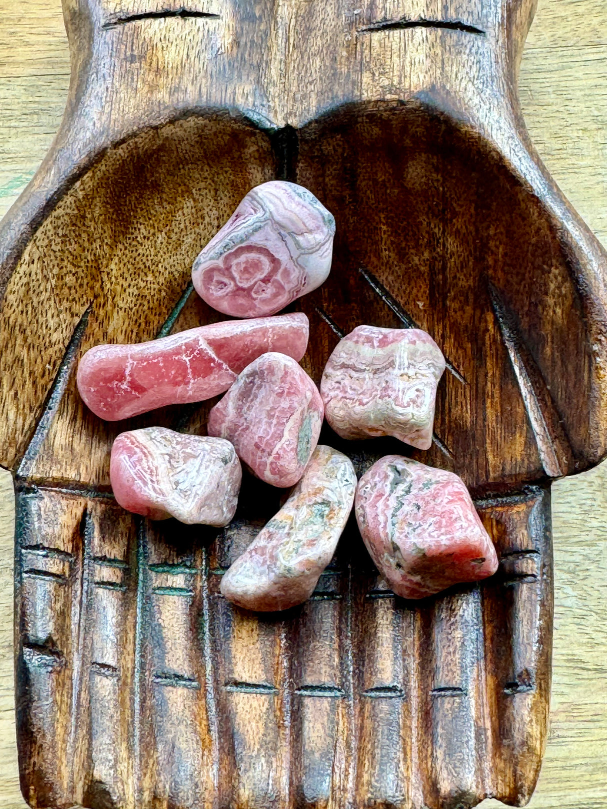 Rhodochrosite tumbled stone in soft pink and white tones — crystal of love, compassion, and emotional healing.