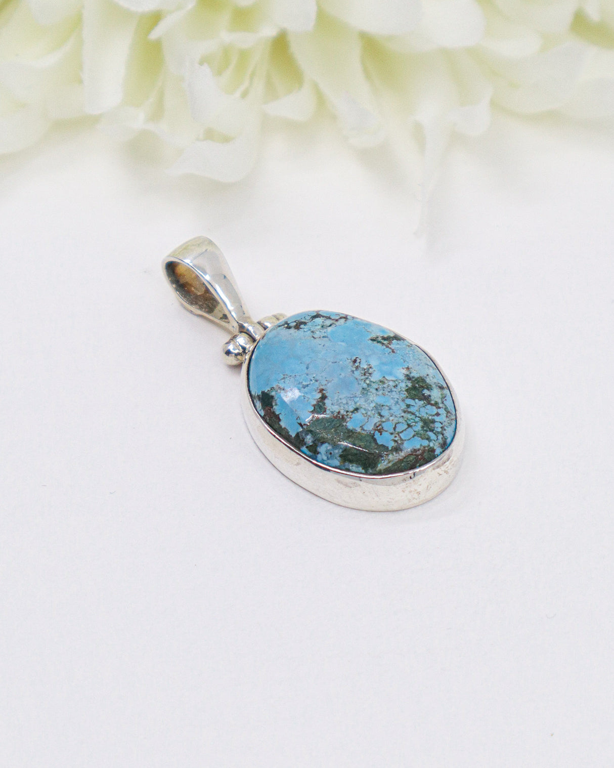 Oval turquoise sterling silver pendant featuring natural sky-blue stone with earthy matrix patterns in a polished silver setting.