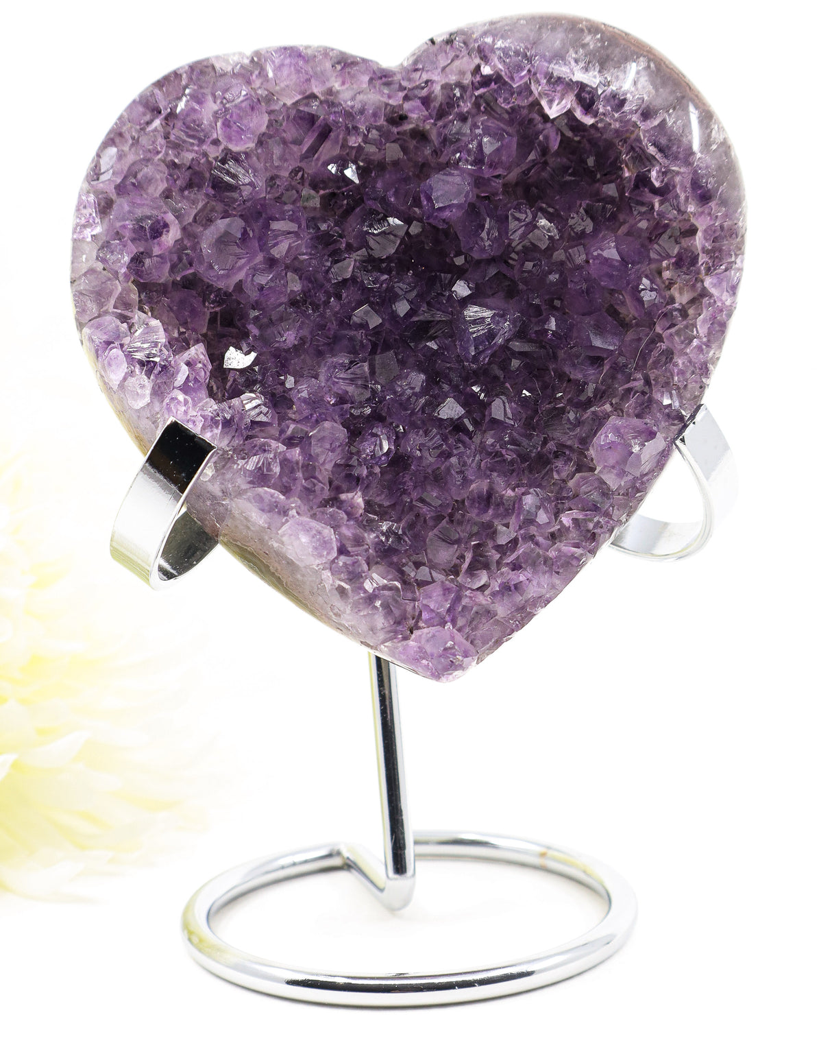 Natural Amethyst Crystal Heart displayed on a metal stand featuring sparkling purple druzy crystals associated with emotional healing, self-love, peace and spiritual growth.