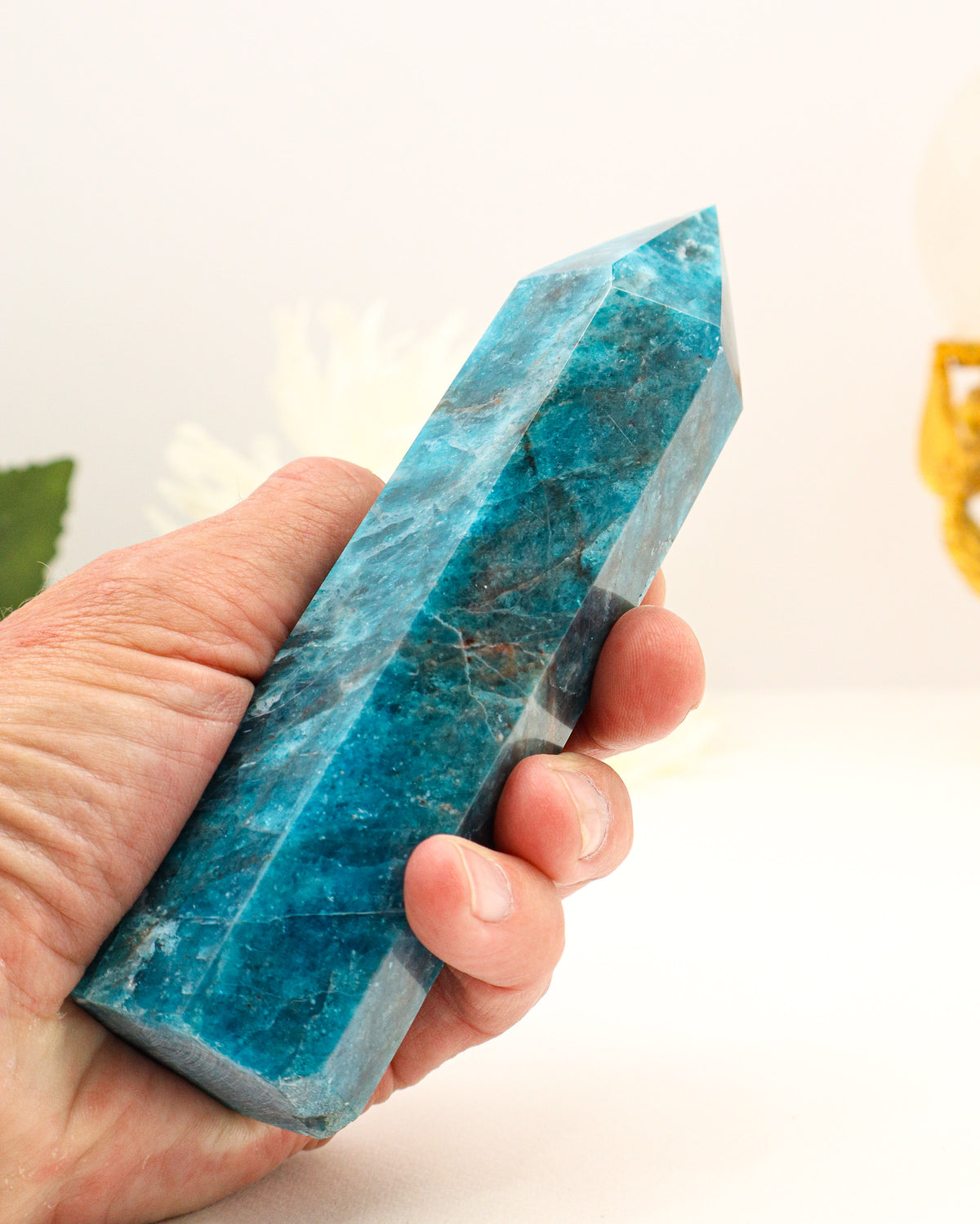 Large natural Blue Apatite crystal tower 476g measuring 15cm, polished six-sided point with vibrant ocean-blue, turquoise and teal colouring, smoky-grey mineral inclusions and natural white veining.