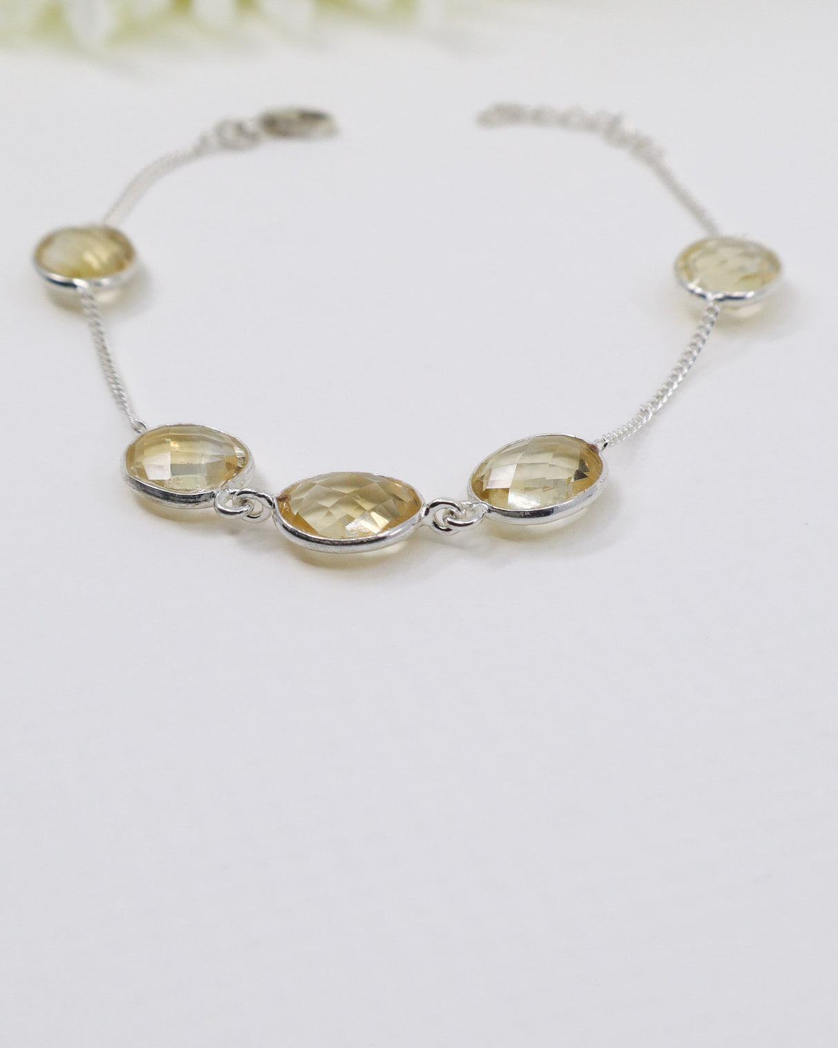 Faceted Citrine sterling silver bracelet displayed beside ruler on wooden background showing delicate gemstone spacing and adjustable chain.