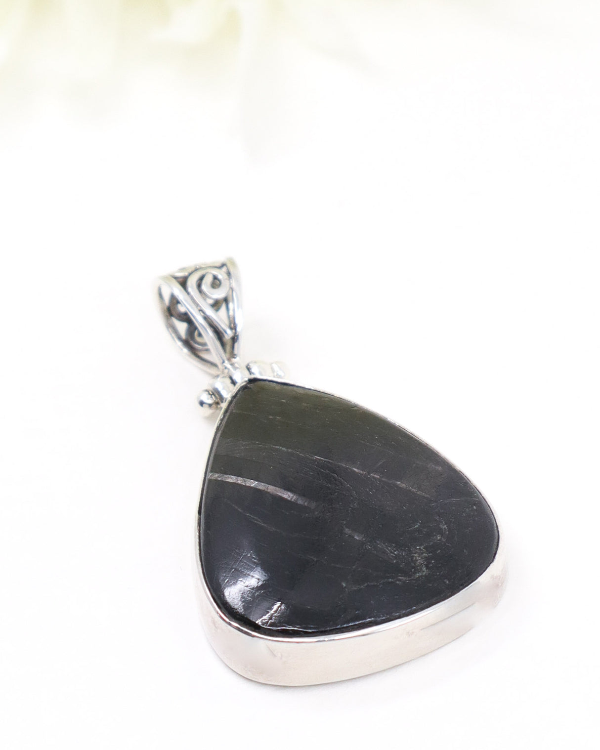 Sterling silver Hypersthene pendant with polished dark triangular gemstone featuring natural silvery flash on white background.