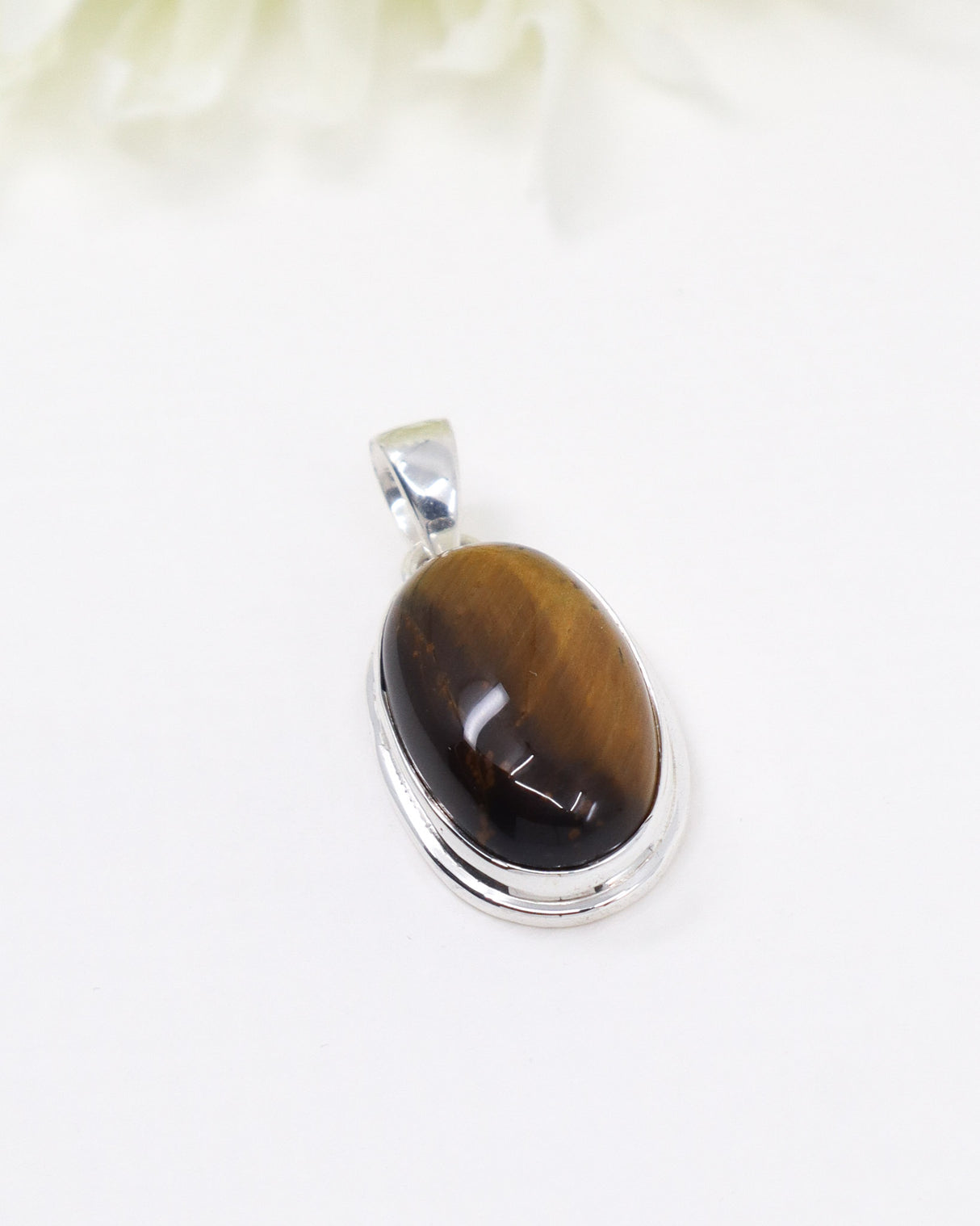 Sterling silver Tiger Eye pendant with polished oval golden-brown gemstone displaying natural chatoyancy on white background.