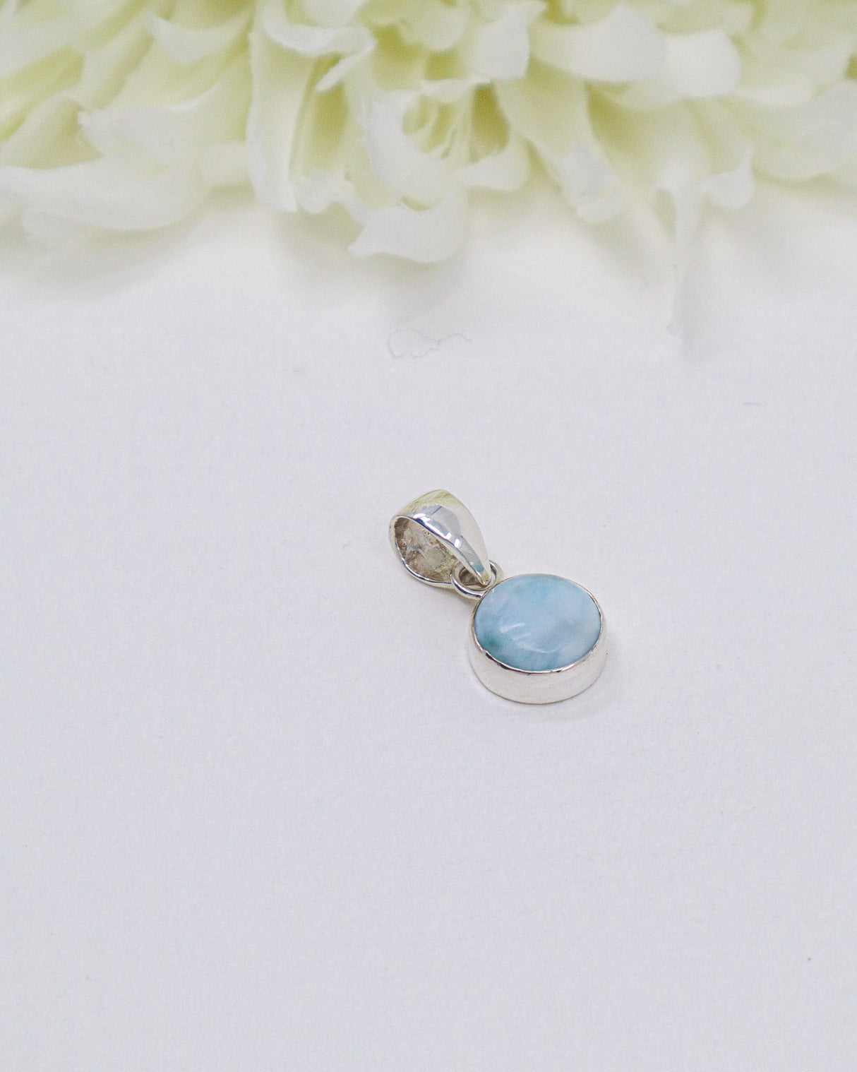 Petite round Larimar silver pendant featuring soft sky-blue and white ocean-like marbling set in polished sterling silver bezel.