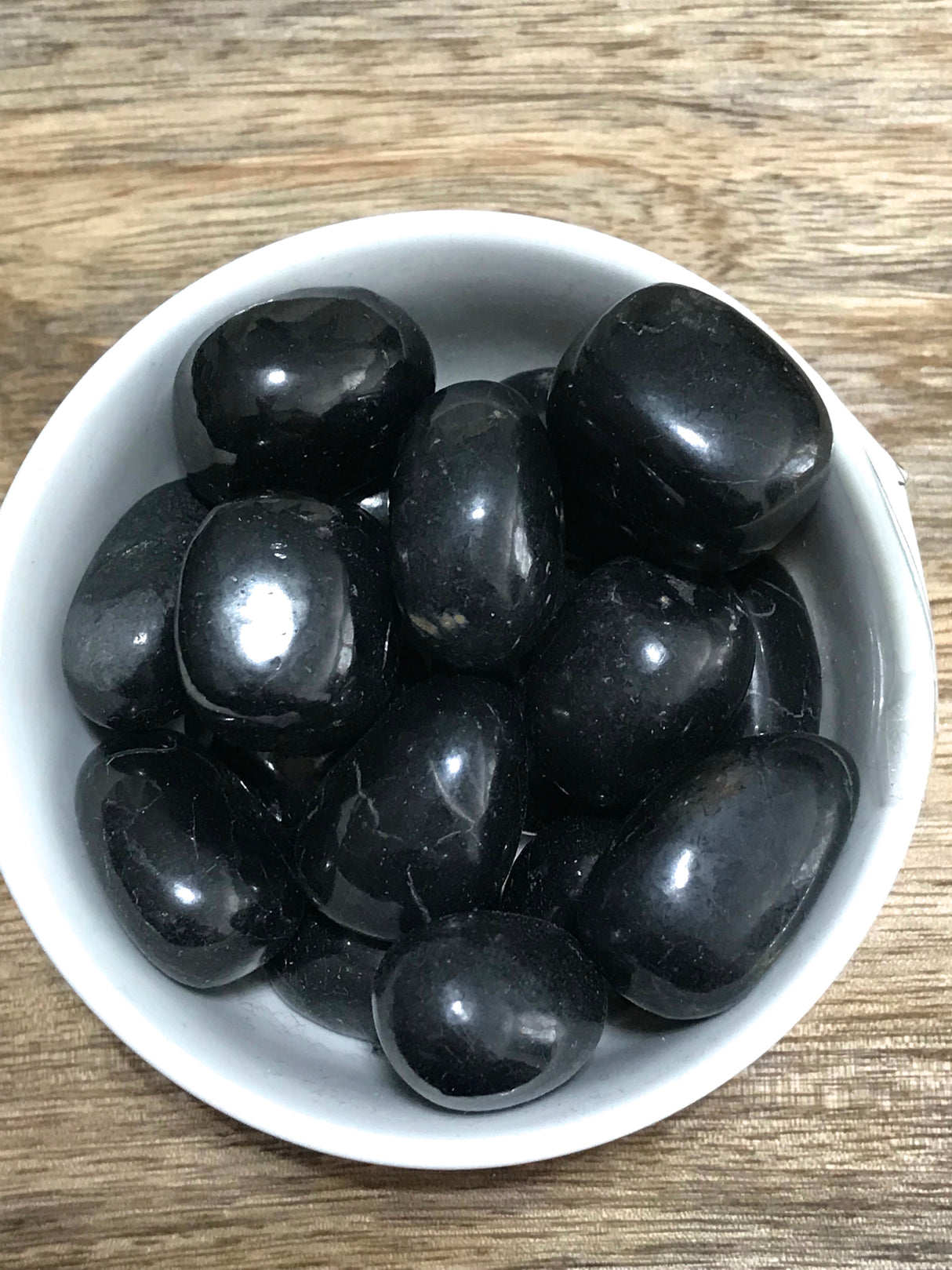 Shungite tumbled stone in glossy black — crystal of protection, purification, and grounding energy.