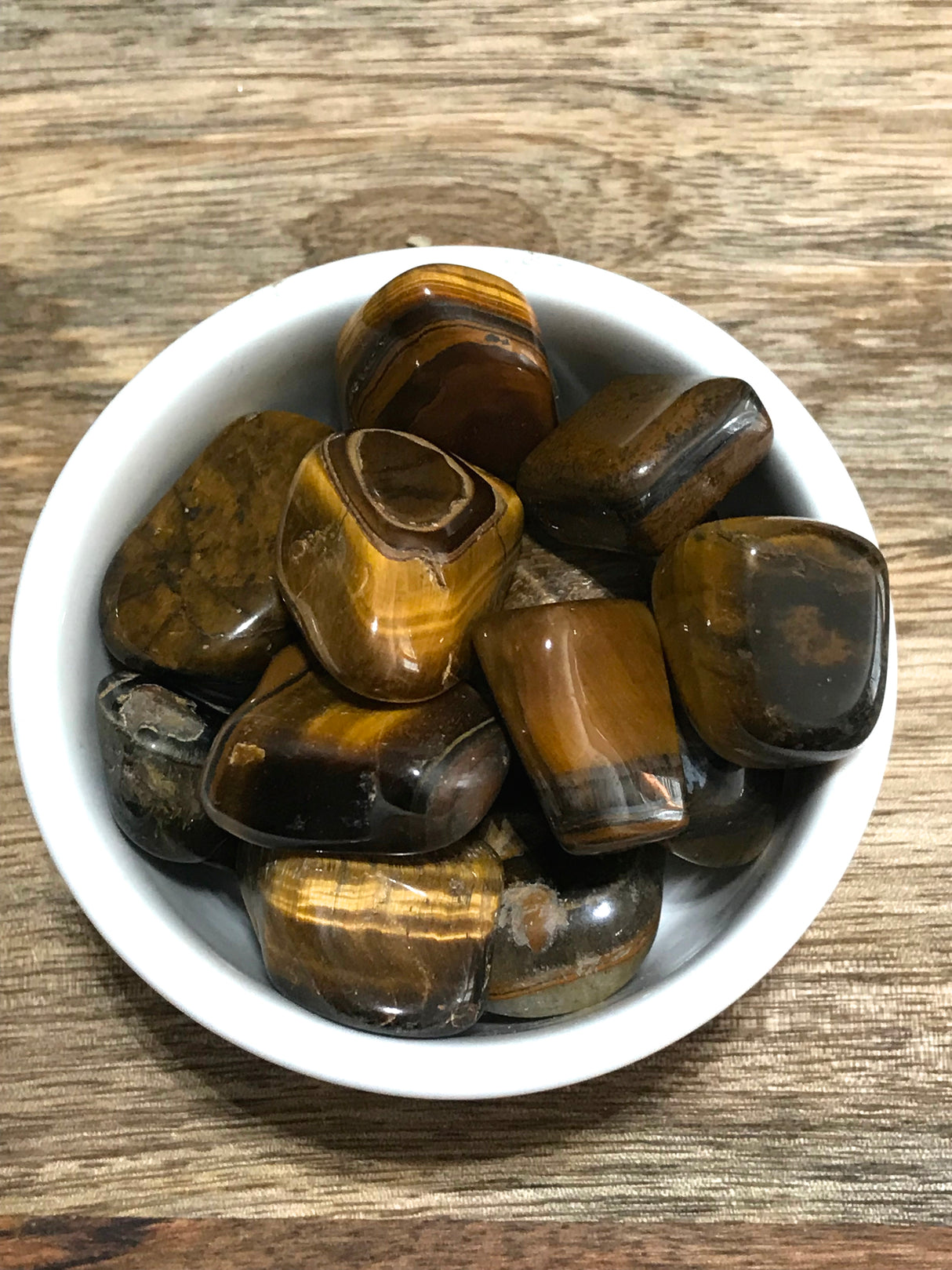 Gold Tiger Eye tumbled stone with golden chatoyant bands — crystal of courage, confidence, and protection.