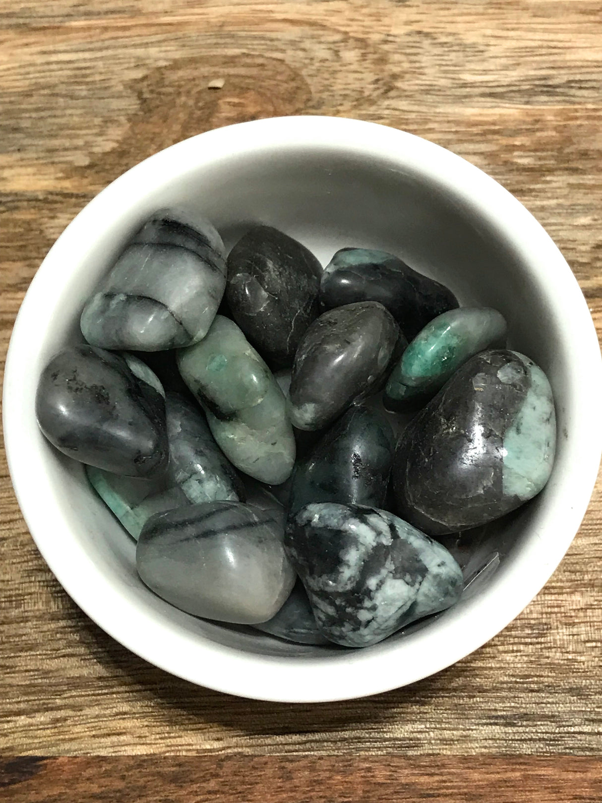 Emerald tumbled stone in deep green tones — crystal of love, wisdom, and heart healing