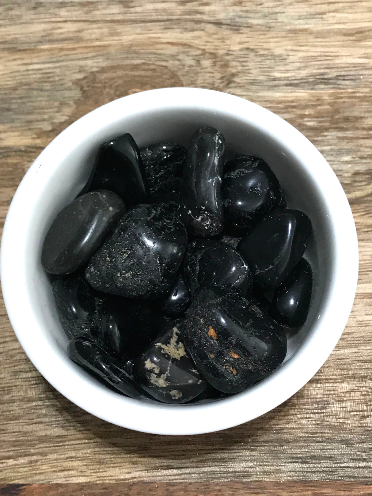 Black Tourmaline tumbled stone in glossy black tones — crystal of protection, grounding, and purification.
