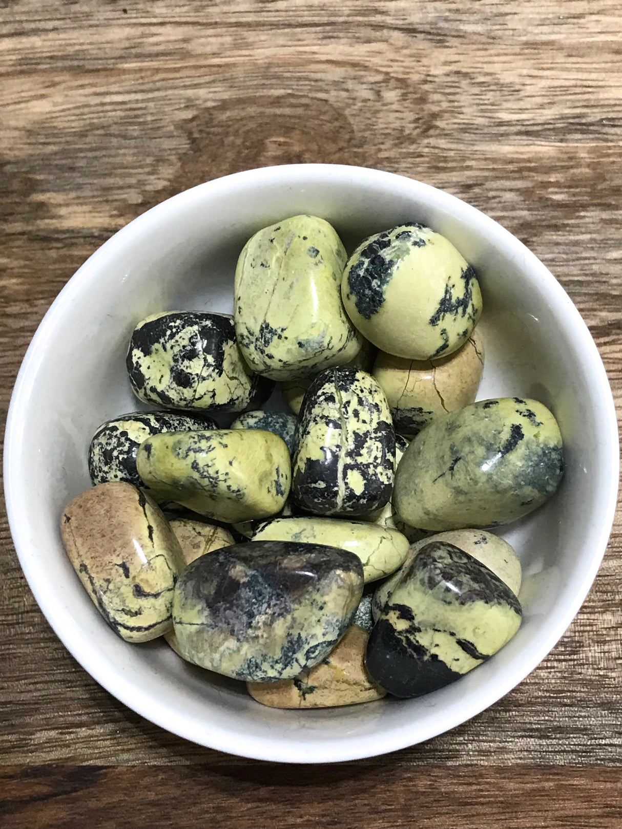 Serpentine tumbled stone in green tones — crystal of healing, awakening, and kundalini energy.