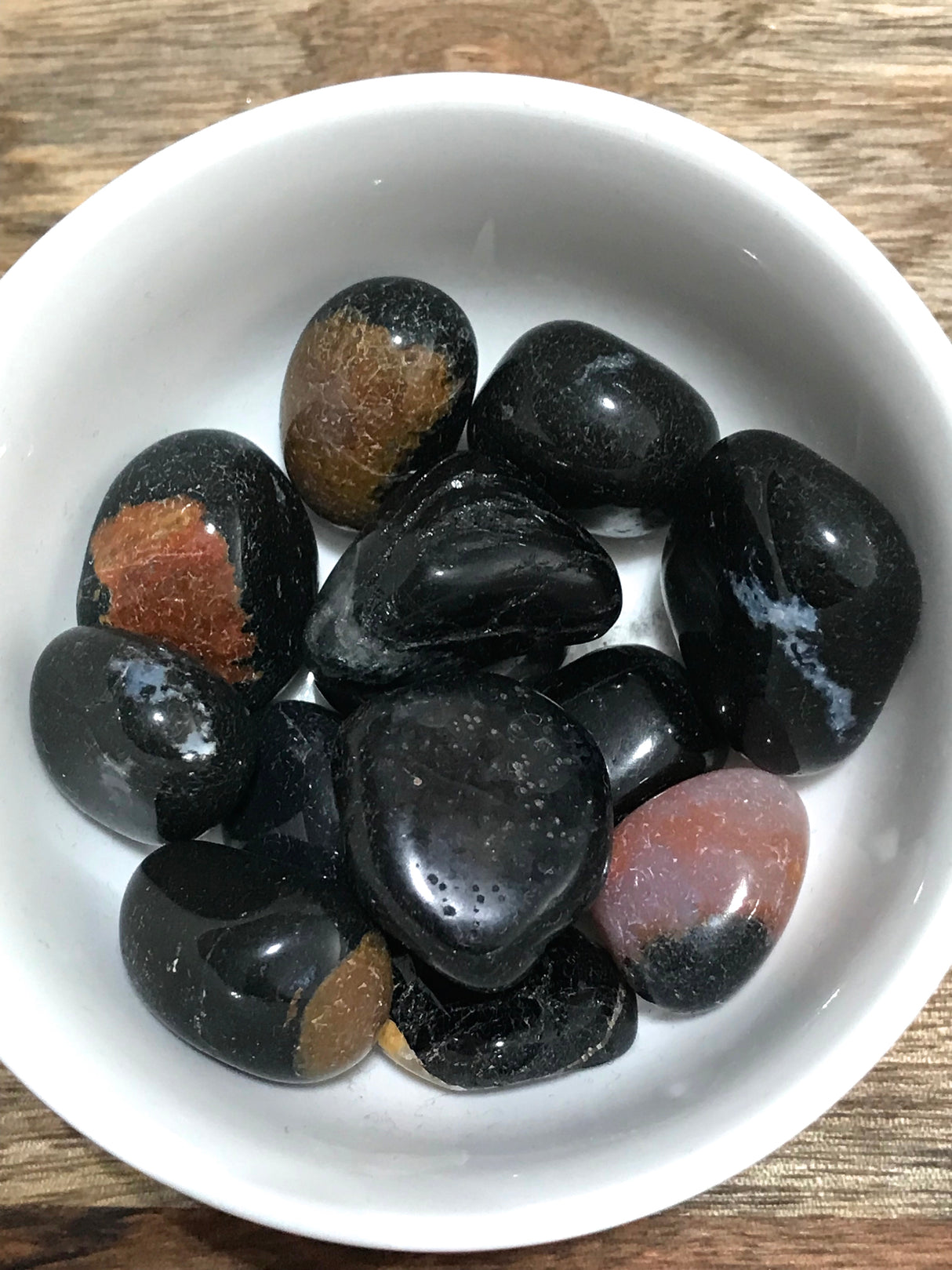 Sardonyx tumbled stone with red, brown, and black bands — crystal of strength, protection, and confidence.