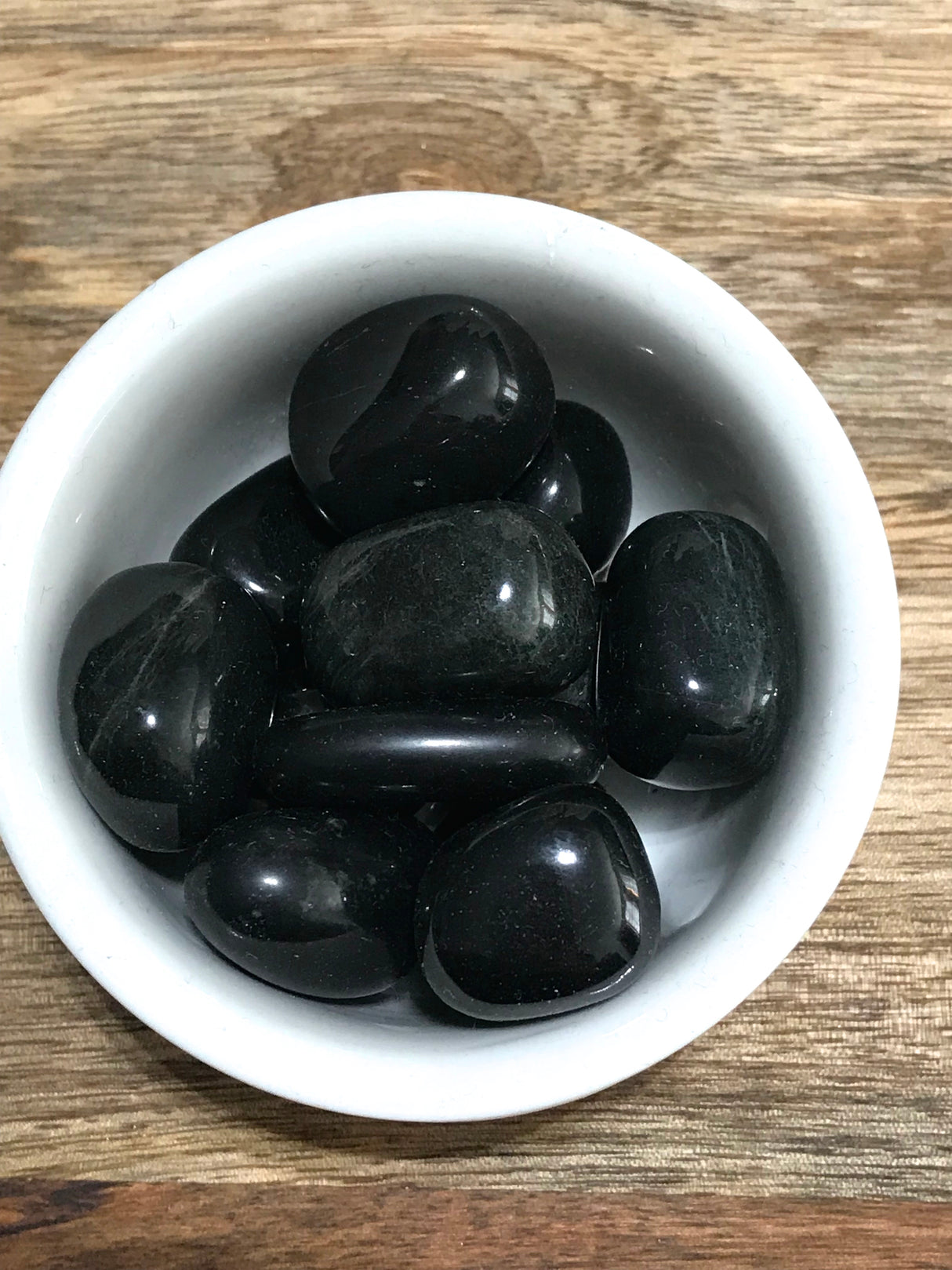 Onyx tumbled stone in deep black tones — crystal of strength, protection, and inner power.