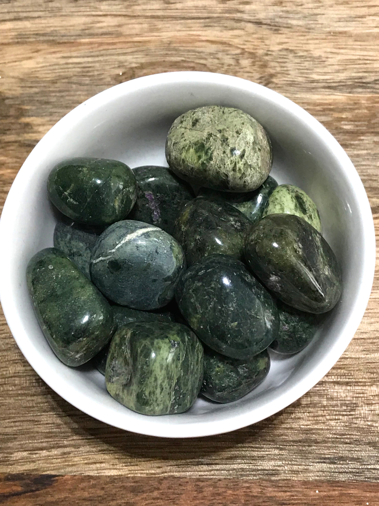 Nephrite Jade tumbled stone in deep green tones — crystal of harmony, protection, and prosperity.