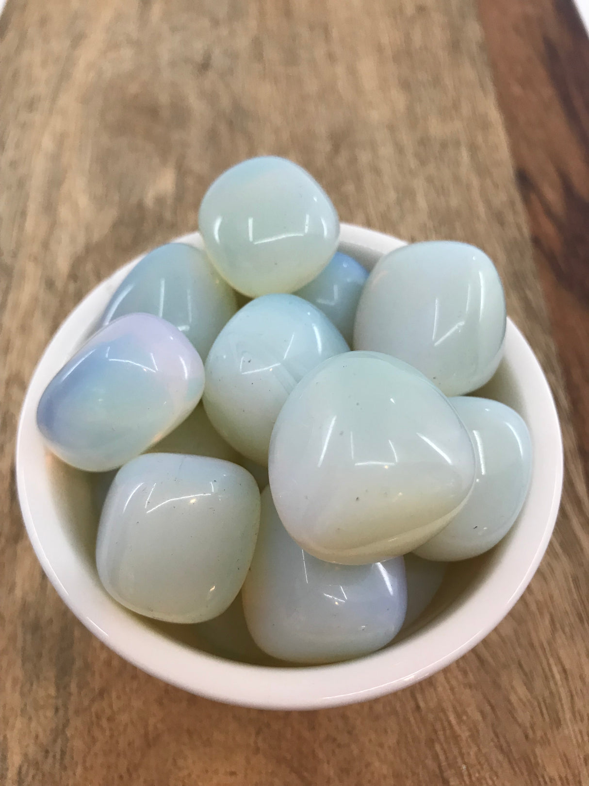 Opalite tumbled stone with iridescent white and blue tones — crystal of serenity, transformation, and spiritual connection.