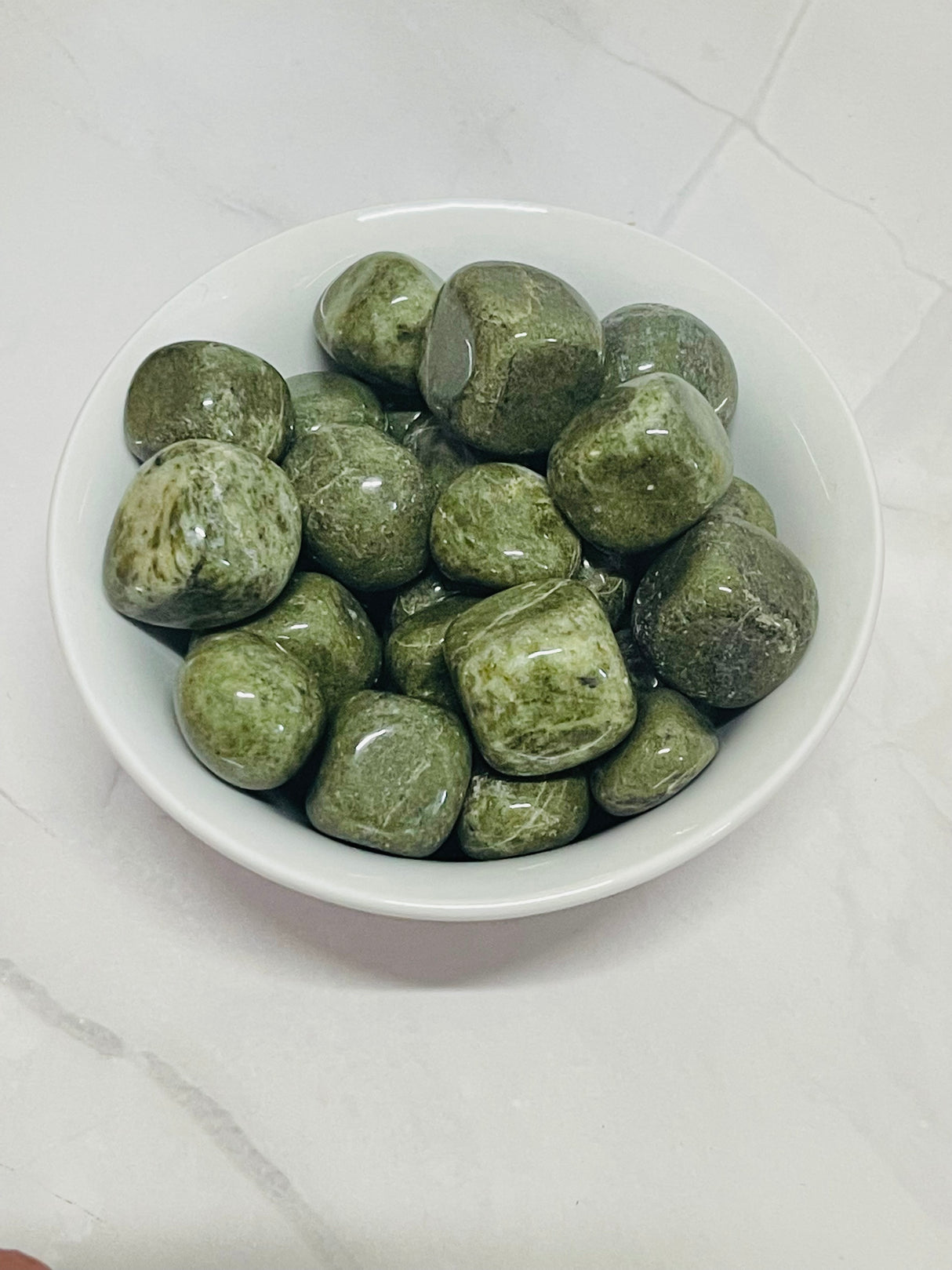 Vesuvianite tumbled stone in olive-green tones — crystal of courage, growth, and heart alignment.