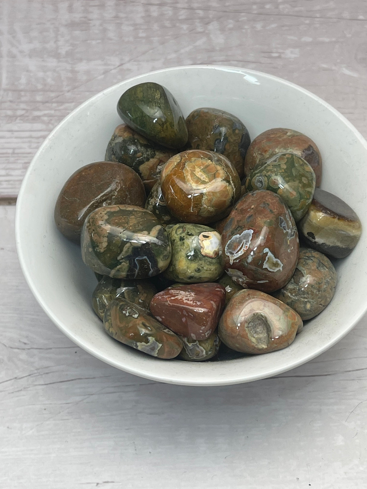 Rhyolite tumbled stone with green, cream, and brown patterns — crystal of growth, creativity, and emotional strength.