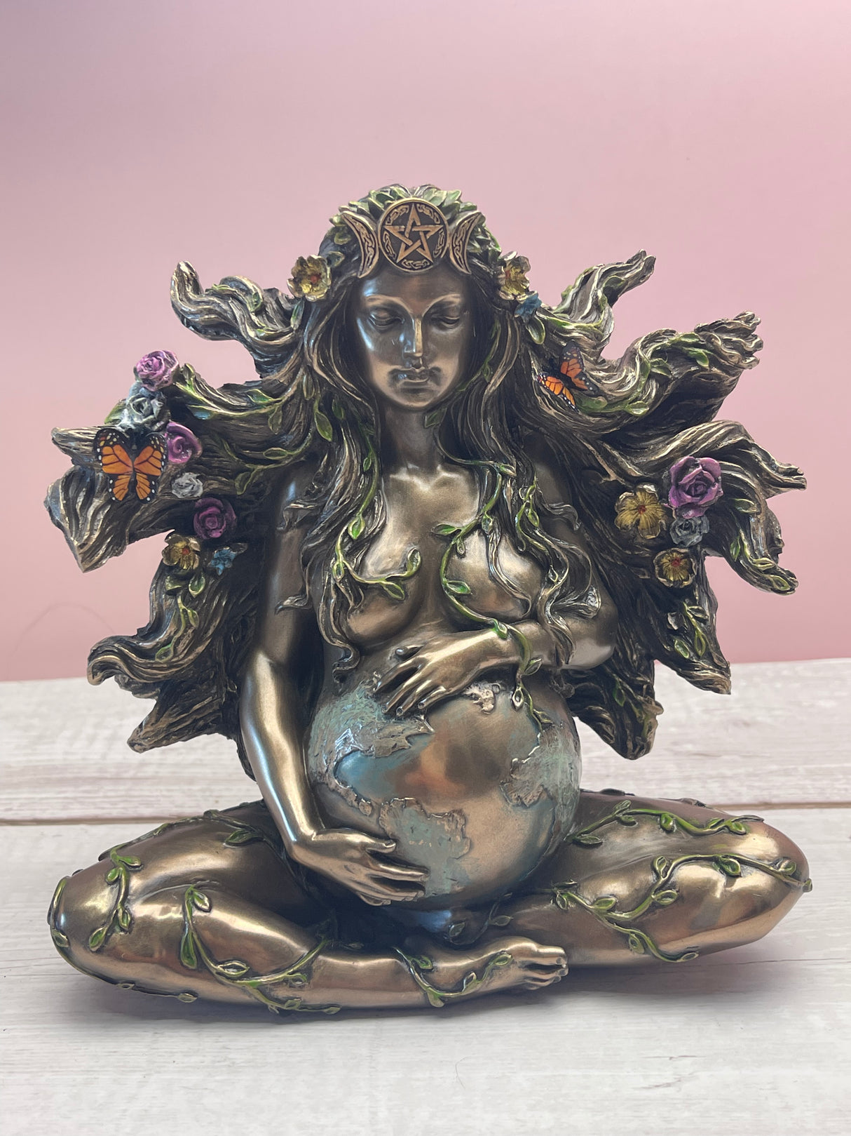 "Gaia bronze statue with triple moon crown, flowers and butterflies in her hair, holding Earth in her belly – symbol of Mother Earth"
