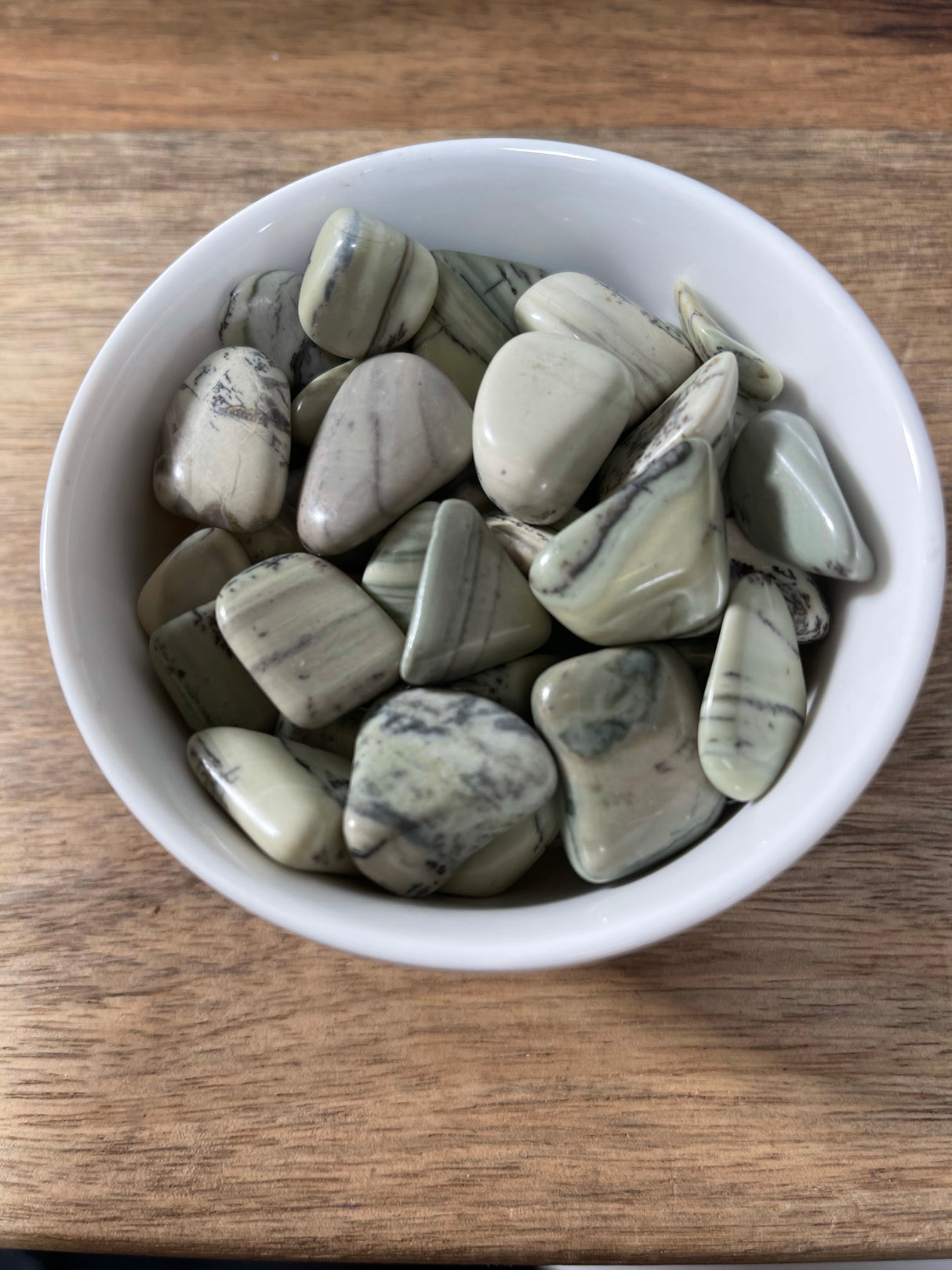 Infinity Stone tumbled crystal in soft green and cream tones — stone of eternal energy, healing, and spiritual connection.