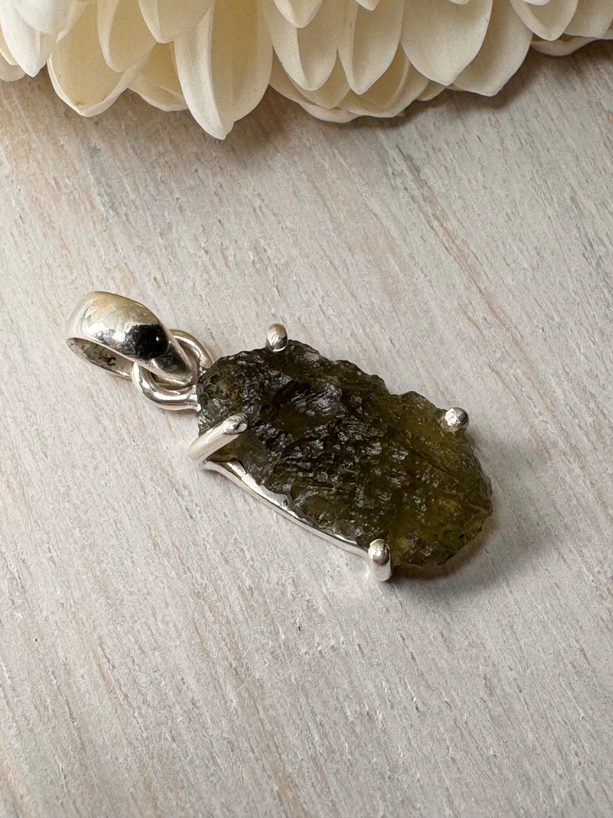 2.28g Moldavite silver pendant in claw setting, with natural raw surface texture on neutral background