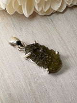 2.28g Moldavite silver pendant in claw setting, with natural raw surface texture on neutral background