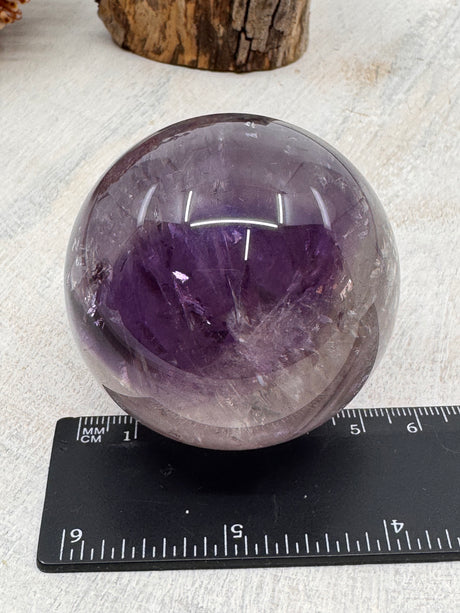 Amethyst Sphere – violet crystal sphere symbolising aura cleansing, dream healing and spiritual renewal, Inspired By 3 Australia. with ruler

