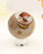 Polished Polychrome Jasper crystal sphere with natural earthy brown, cream and terracotta patterns displayed on a clear stand against a soft cream background.