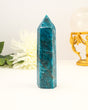 Polished Blue Apatite crystal tower with vibrant ocean-blue colouring photographed on a cream background with floral styling.