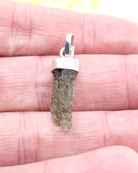 Natural Czech Moldavite pendant in sterling silver featuring a raw elongated green Moldavite crystal with authentic texture and transformational energy.