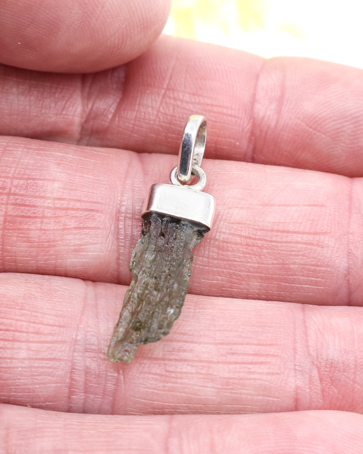 Natural Czech Moldavite pendant in sterling silver featuring a raw elongated green Moldavite crystal with authentic texture and transformational energy.