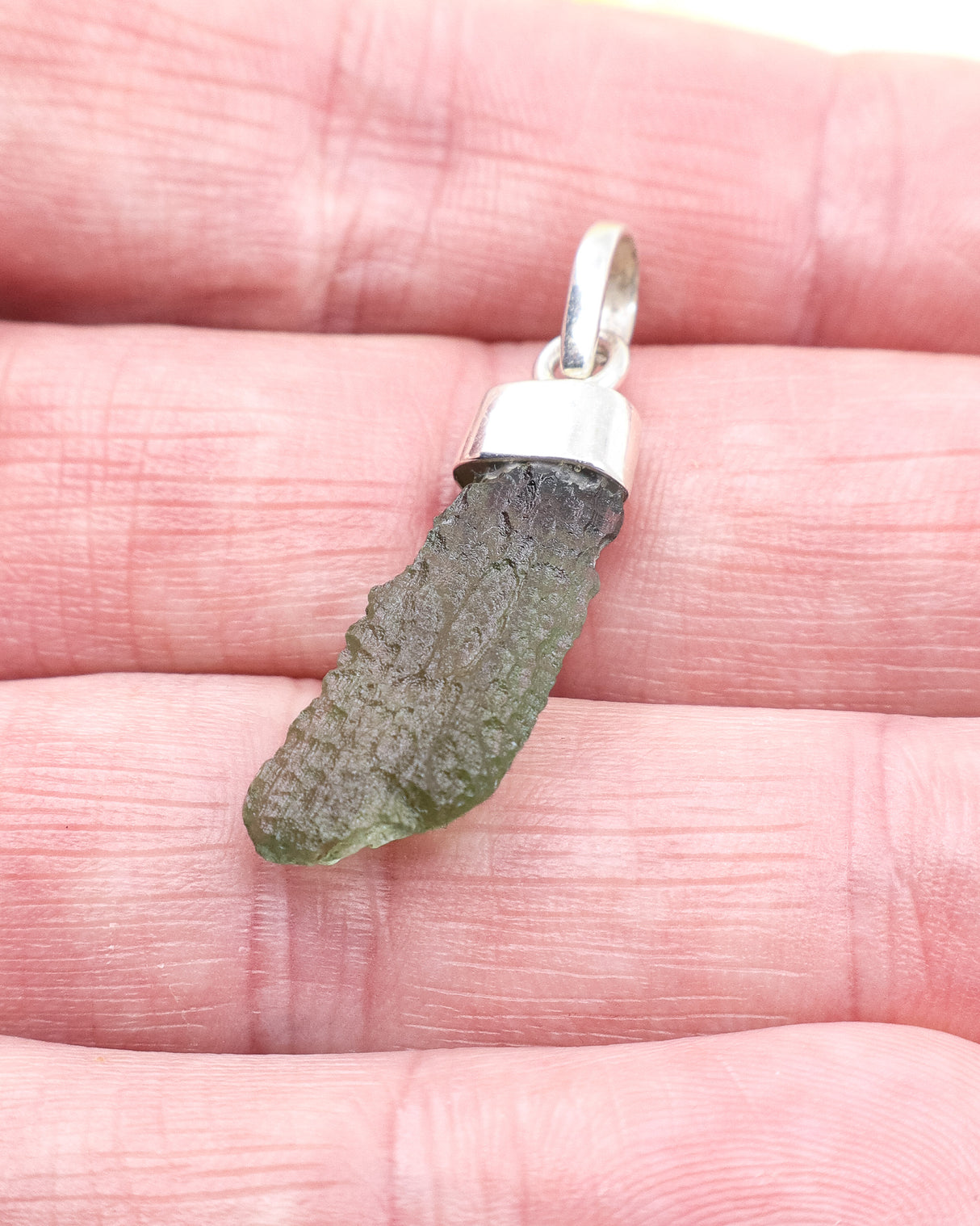 Natural Czech Moldavite pendant in sterling silver featuring an elongated raw green tektite with beautiful texture and powerful transformational energy.