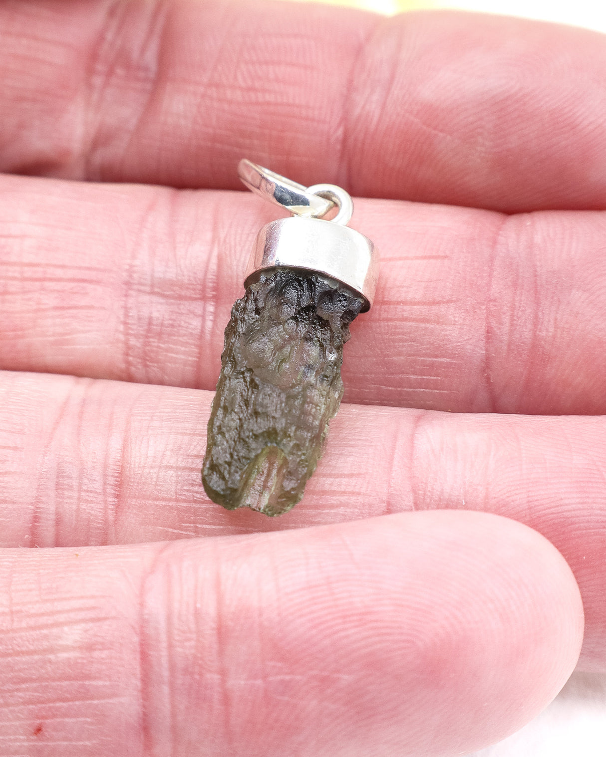 Natural Czech Moldavite pendant in sterling silver featuring an elongated raw green Moldavite crystal with beautiful texture and powerful transformational energy.