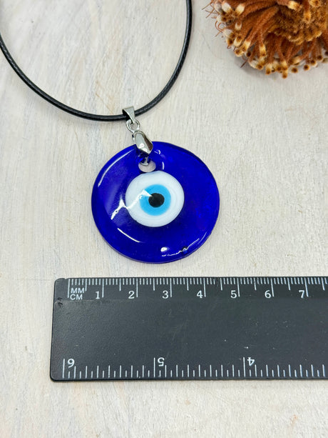 Handmade Evil Eye lampwork pendant 40x7mm platinum tone – glass protection amulet for luck, energy shielding and clarity – next to a ruler