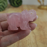 Rose quartz elephant carving displayed on wooden surface beside ruler showing size