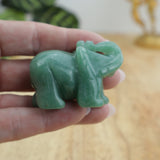 Green aventurine elephant carving displayed on wooden surface beside ruler showing size