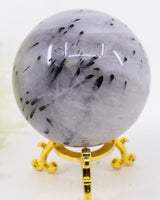 Natural Black Tourmalinated Quartz Crystal Sphere 363g with striking black tourmaline inclusions in polished clear quartz on a gold display stand.