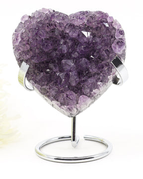 Natural Amethyst Crystal Heart displayed on a metal stand featuring deep purple druzy crystal formations associated with emotional healing, harmony and spiritual growth.