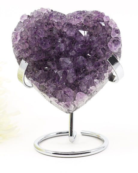 Natural Amethyst Crystal Heart displayed on a metal stand featuring deep purple druzy crystal formations associated with emotional healing, harmony and spiritual growth.