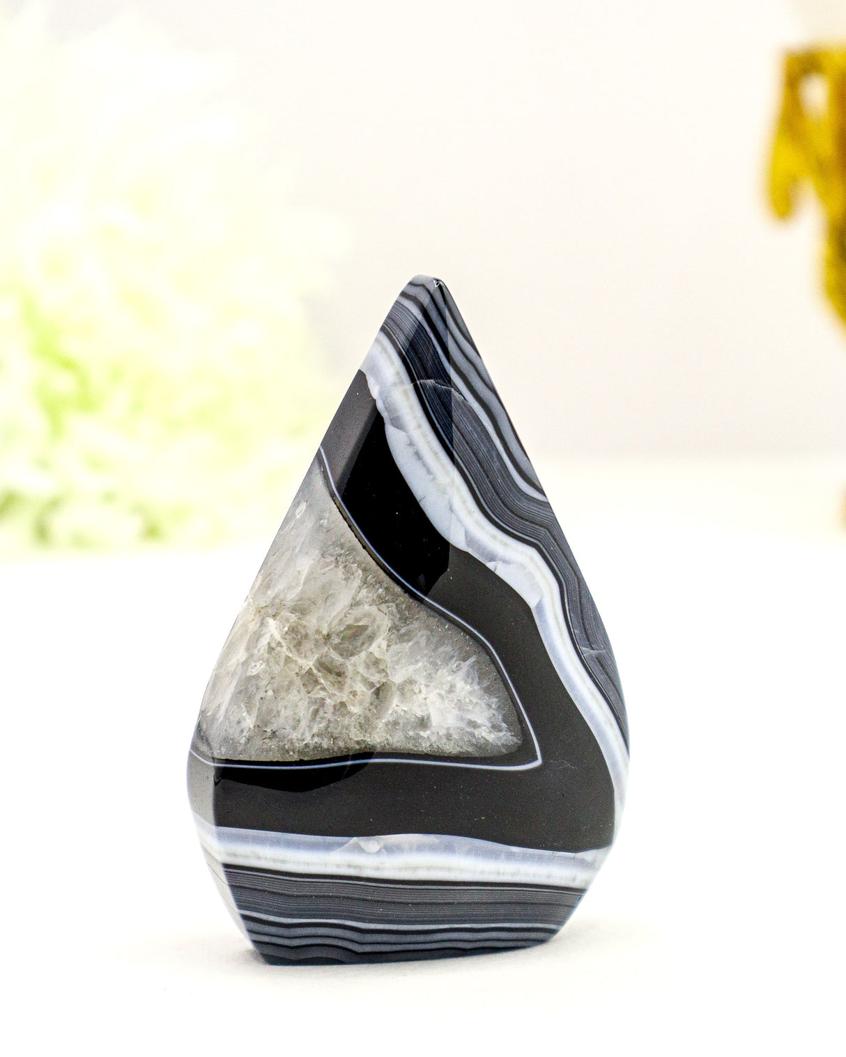 Polished Black Banded Agate flame carving with white crystalline banding and natural druzy detail displayed on a soft cream background.