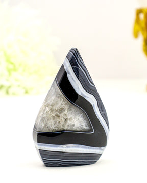 Polished Black Banded Agate flame carving with white crystalline banding and natural druzy detail displayed on a soft cream background.
