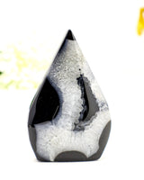 Polished Black Banded Agate flame crystal with natural white druzy inclusions and glossy banding displayed on a soft cream background.