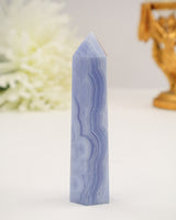 Polished Blue Lace Agate crystal tower with soft pastel blue natural banding on a cream background.
