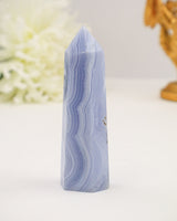 Polished Blue Lace Agate crystal tower with soft pastel blue banding on a cream background.