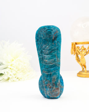 Hand carved blue apatite snake crystal carving with detailed scales and vibrant blue tones on white background