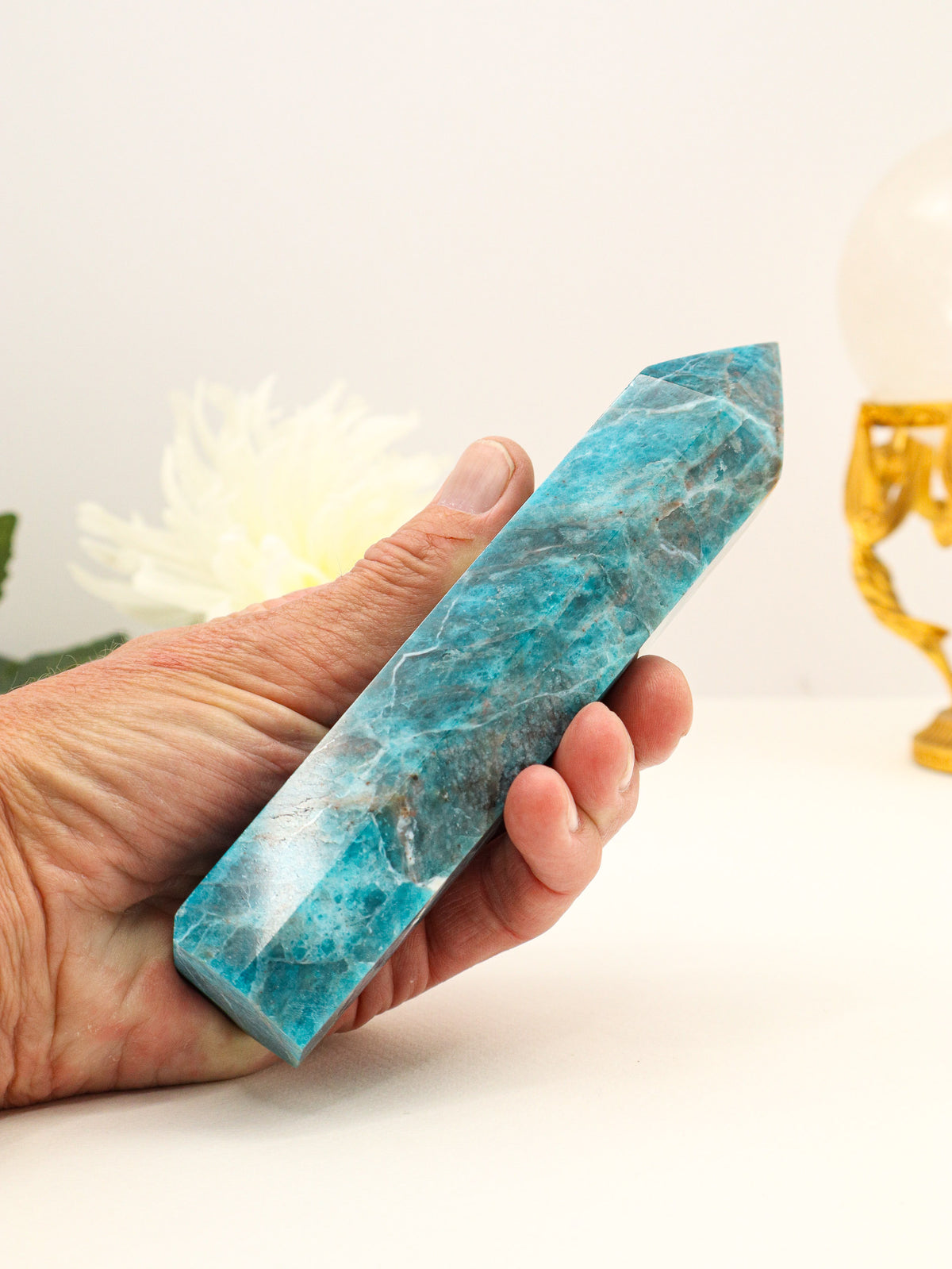 Large 470g Blue Apatite crystal point held in hand, displaying vibrant teal-blue colouring, natural mineral patterns and polished faceted termination.