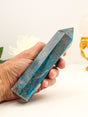 Large 545g Blue Apatite crystal point held in hand, displaying rich turquoise and ocean-blue colouring with contrasting earthy mineral inclusions.