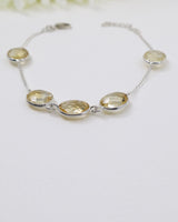 Faceted Citrine sterling silver bracelet displayed beside ruler on wooden background showing delicate gemstone spacing and adjustable chain.